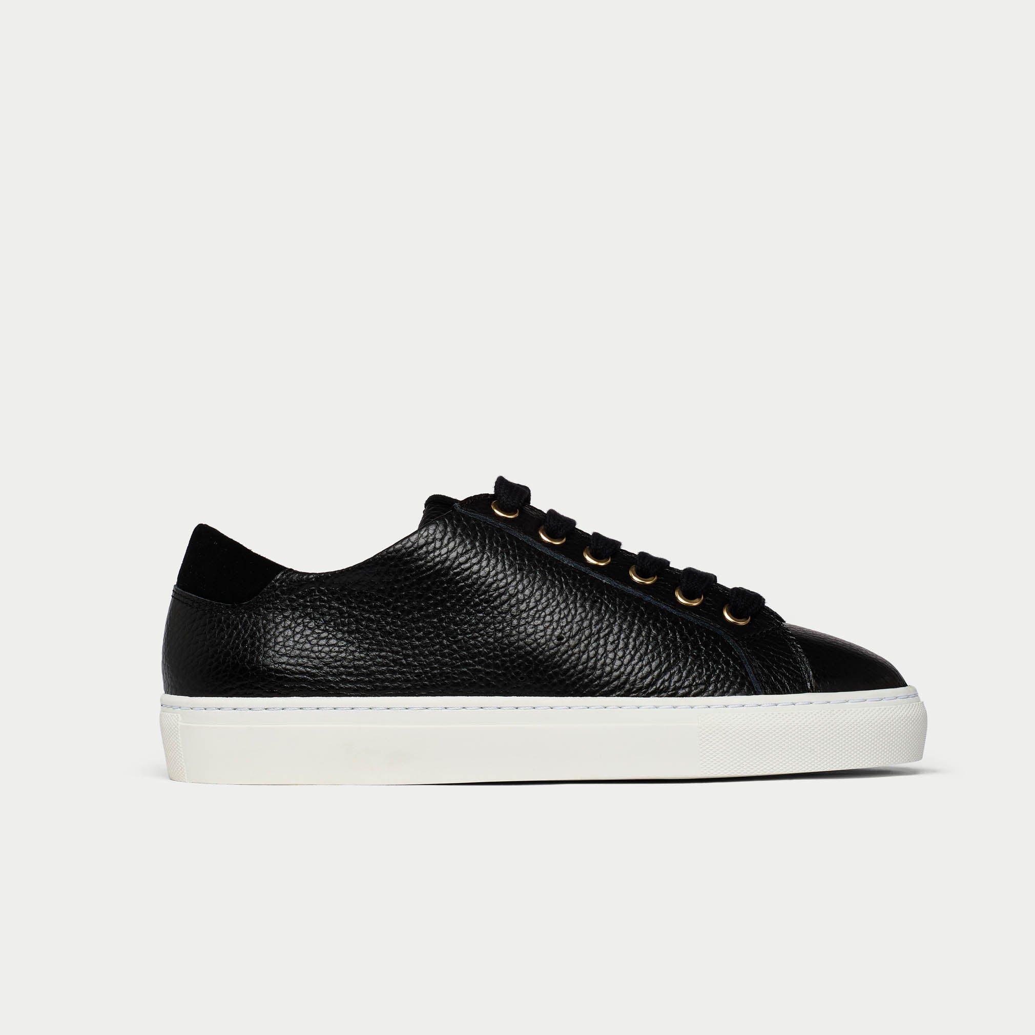 Black leather sneaker with white sole on a light gray background