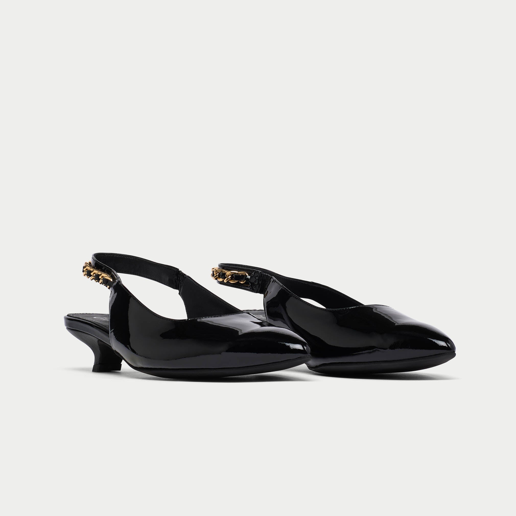 Pair of black low-heeled Thea shoes with gold accents on a white background