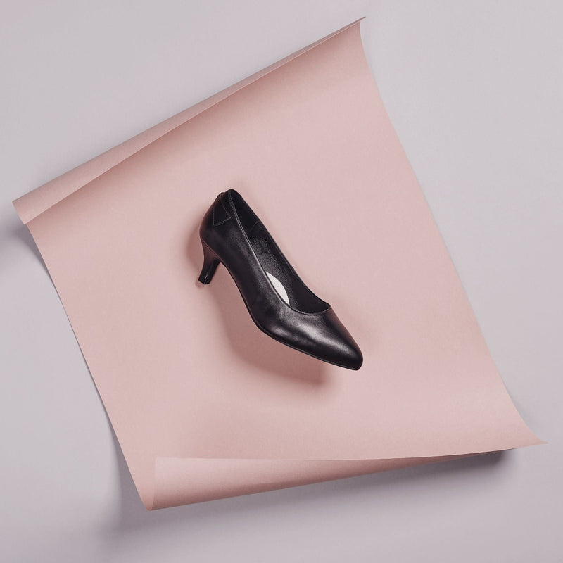 black leather low heel shoe on a pink background